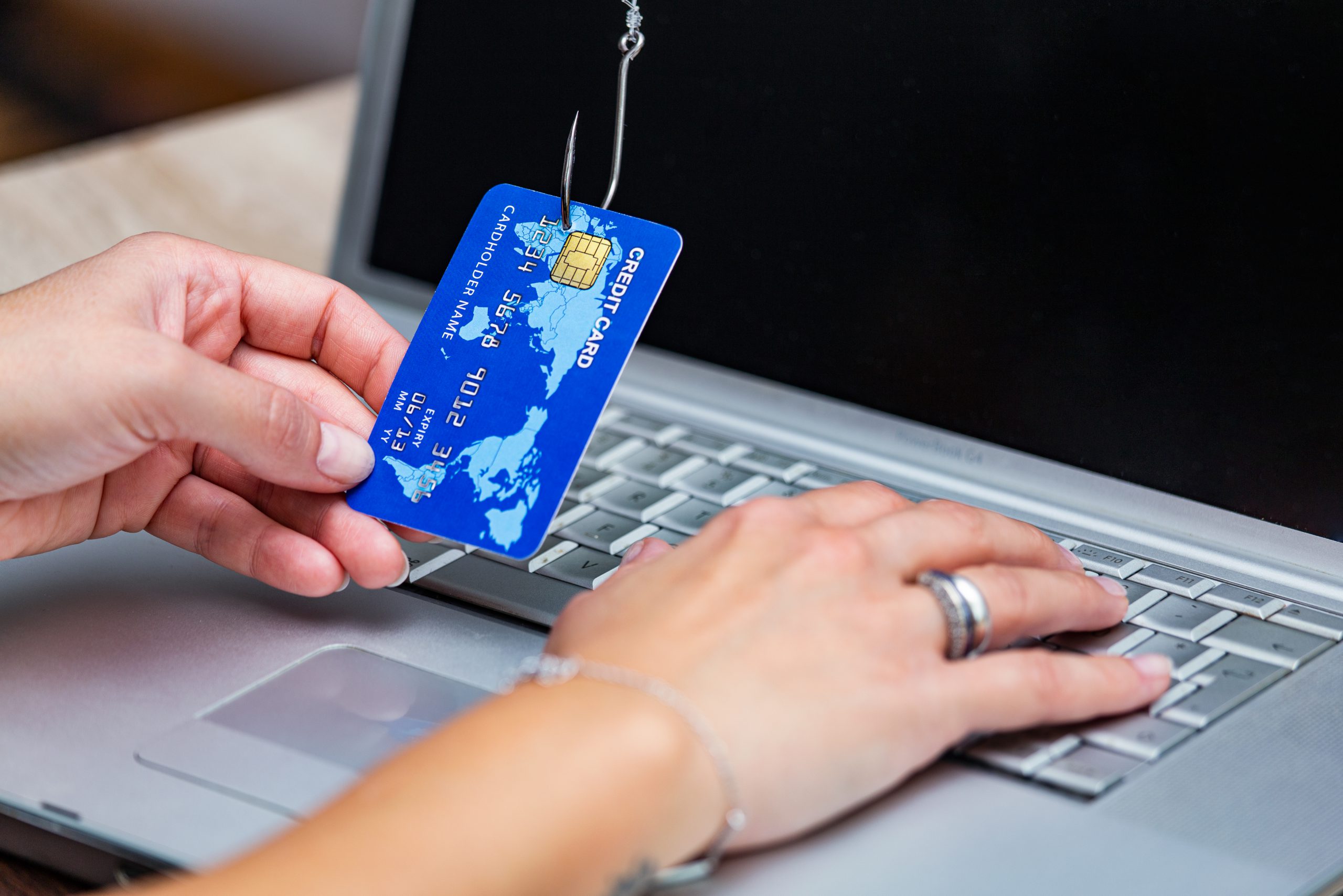 Credit card phishing. Phishing scam with credit card in fishing hook. Woman typing her credit card information on scam site